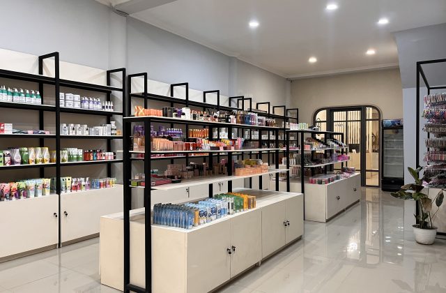 A bright, modern beauty store interior in Waingapu features black-framed shelves filled with colorful skincare and makeup products, with an arched doorway in the background.