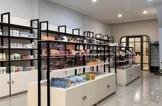 A bright, modern beauty store interior in Waingapu features black-framed shelves filled with colorful skincare and makeup products, with an arched doorway in the background.
