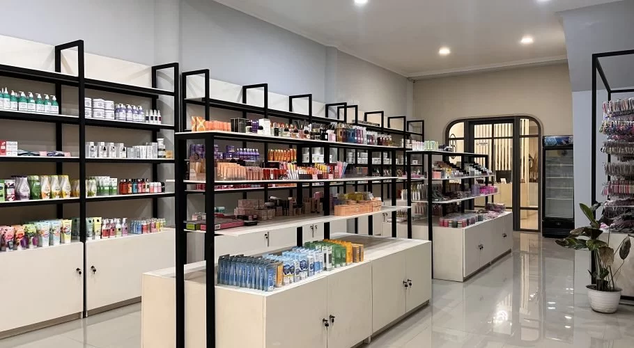 A bright, modern beauty store interior in Waingapu features black-framed shelves filled with colorful skincare and makeup products, with an arched doorway in the background.