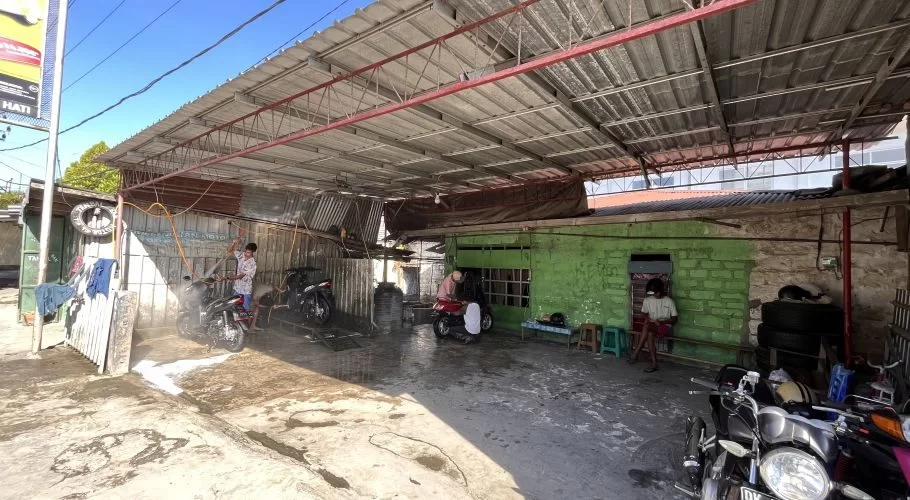 A worker sprays a motorcycle with water and foam at Cathy Julian Motor, an outdoor wash shop in Waikabubak, Sumba.