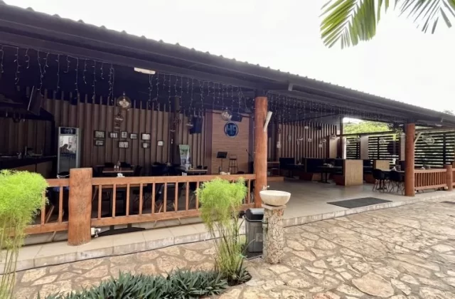 The exterior of HF Restaurant in Tambolaka, Sumba, features a covered patio with wooden pillars, string lights, tables, and a bar area where a person is visible.