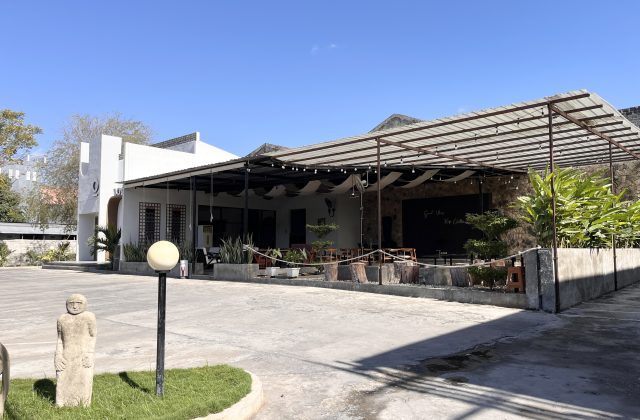 The modern white exterior of Local Tree Cafe & Eatery features an industrial-style outdoor seating area under a metal canopy on a sunny day.