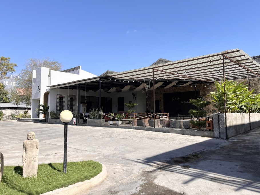 The modern white exterior of Local Tree Cafe & Eatery features an industrial-style outdoor seating area under a metal canopy on a sunny day.