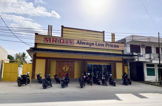 A vibrant yellow MR. DIY store with "Always Low Prices" signage stands under a partly cloudy sky, with numerous motorcycles parked in front.