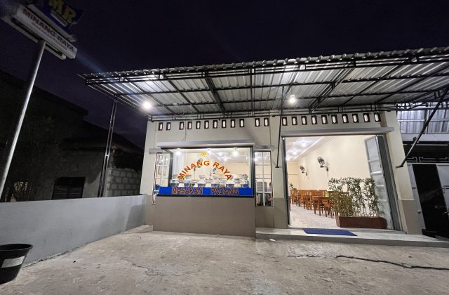 The brightly lit exterior of MR Restaurant in Tambolaka, Sumba, shows its open entrance, a food display counter, and an inviting dining area at night.