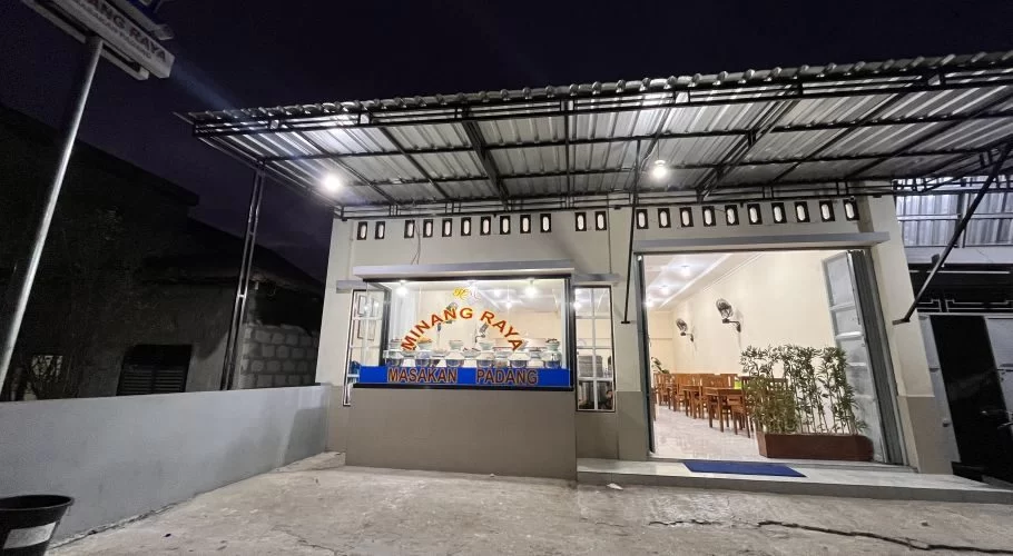 The brightly lit exterior of MR Restaurant in Tambolaka, Sumba, shows its open entrance, a food display counter, and an inviting dining area at night.