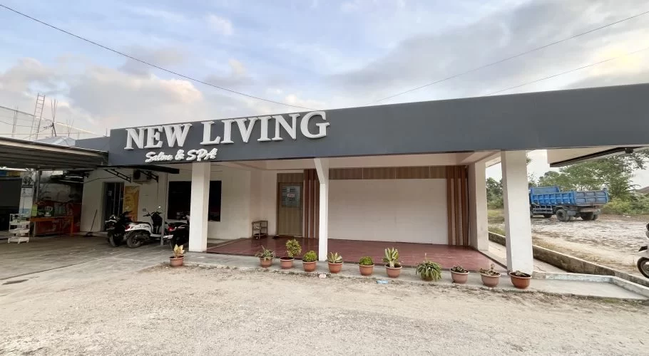 The exterior of New Living Salon & Spa in Waikabubak features a grey facade with white lettering, potted plants, and parked motorbikes under a cloudy sky.