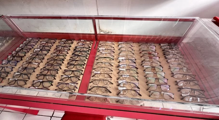 Numerous eyeglasses with various frames are neatly arranged in rows inside a red-trimmed glass display case at Optik International.
