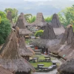 Prai Ijing traditional village in Sumba, Indonesia, shows many conical thatched-roof houses and stone megaliths amidst green trees.