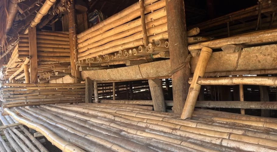 The intricate underside of a traditional Sumba house features a floor of split bamboo planks and walls constructed from thick bamboo poles and wooden beams.