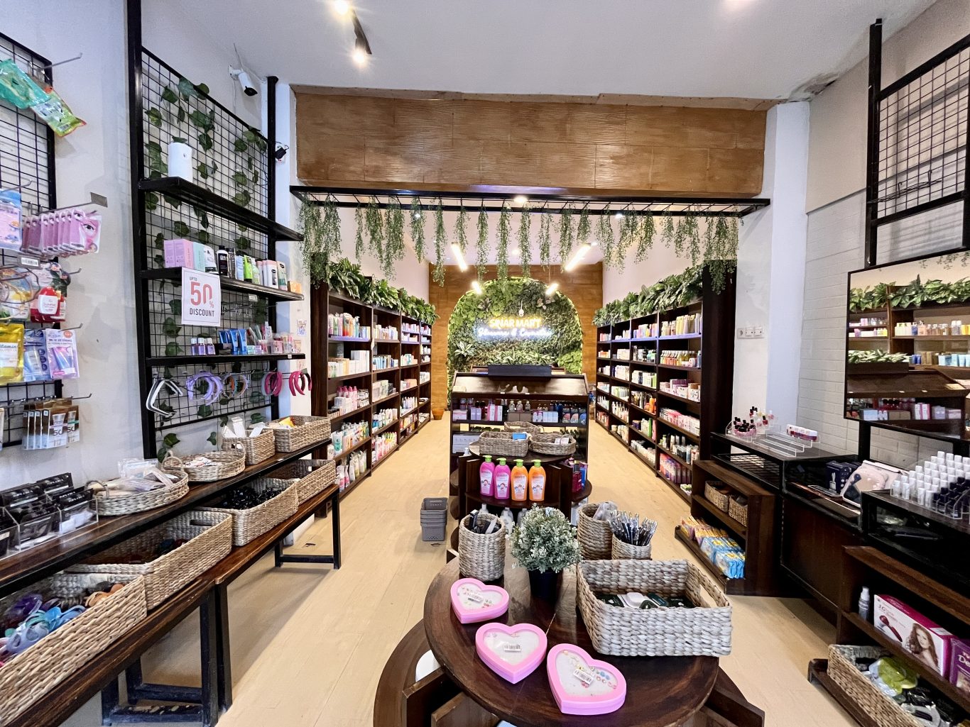 A brightly lit skincare store interior features dark wooden shelves packed with colorful products, wicker baskets, and a green wall with a neon sign at the back.