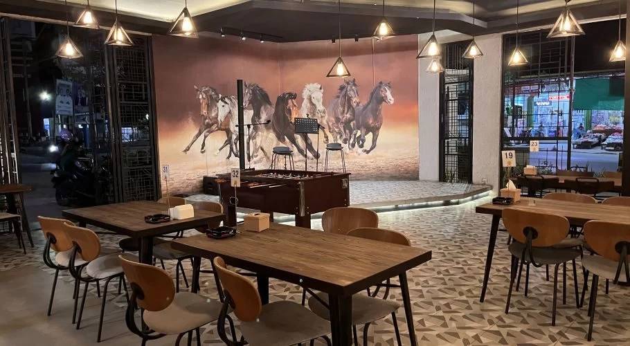 The Sirkey Restaurant interior features wooden tables, chairs, a patterned floor, and a large mural of running horses, with a stage and foosball table.