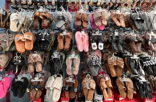 A wall display in Wahyu Store shows hundreds of sandals, flip-flops, and high heels in various colors and styles, hanging neatly on hooks.