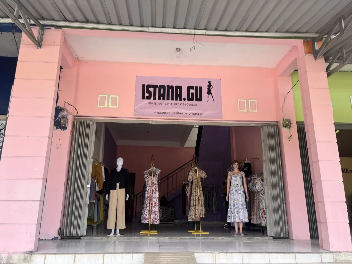 The pink storefront of Istana.Gu fashion store features three mannequins displaying dresses and a black top with beige pants, with more clothes visible inside.