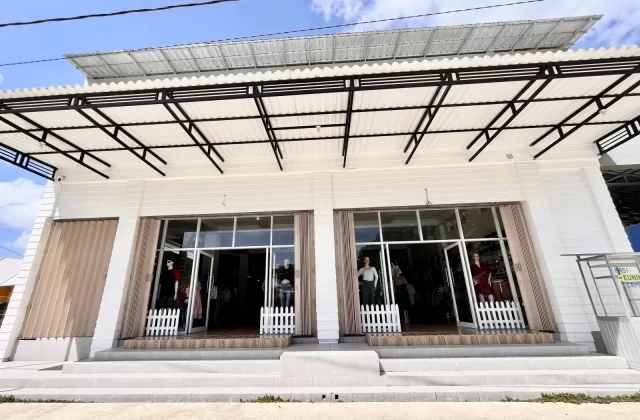 The white Oretz Boutique storefront in Waikabubak, West Sumba, features two glass entrances with mannequins displaying clothing under a black metal awning and blue sky.
